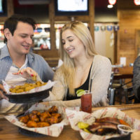 A photograph of a smiling couple eating fried pickles
