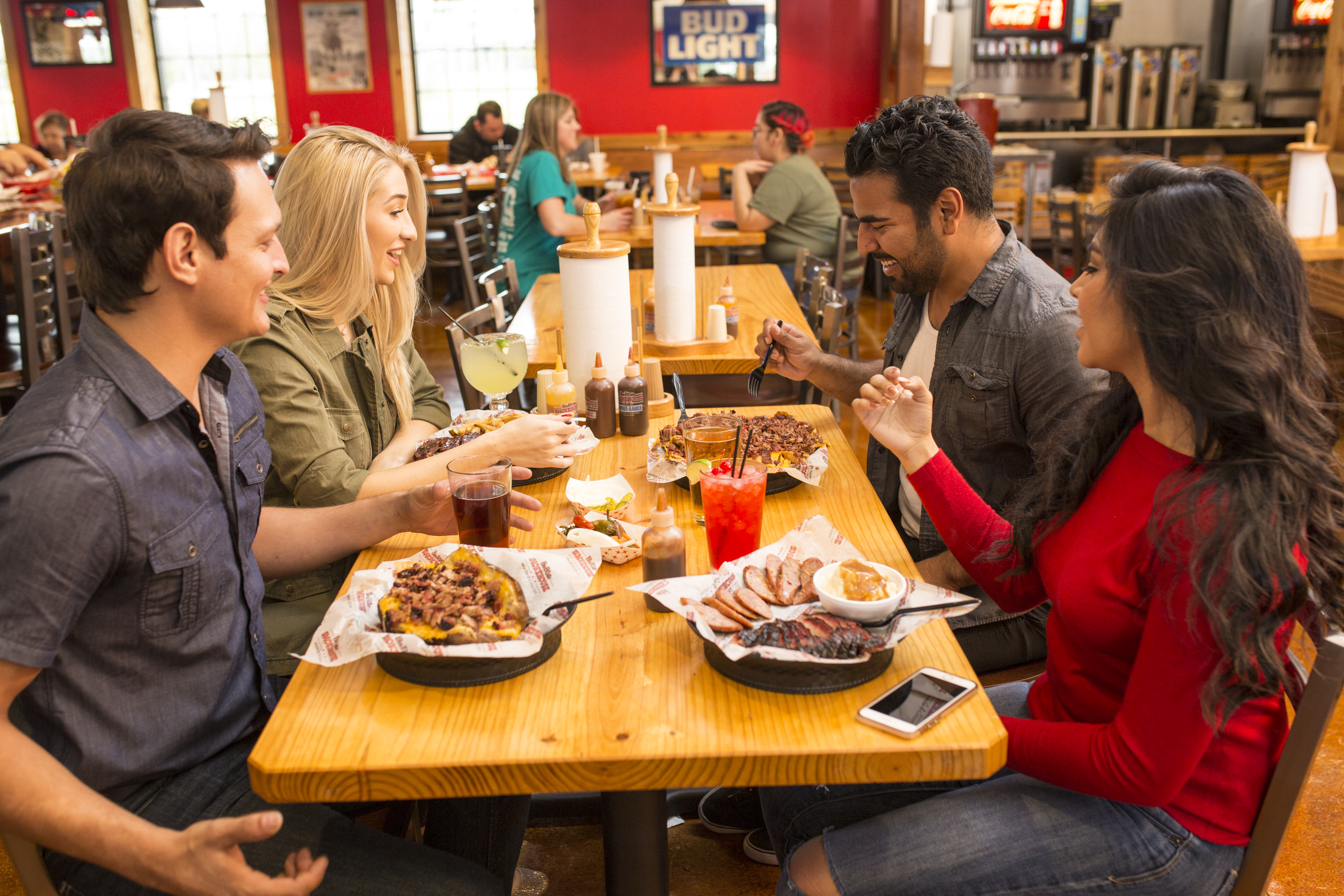 A photograph of a happy group of people drinking and eating barbecue nachos